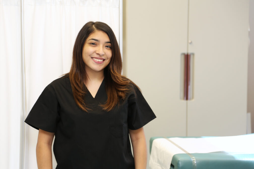 Smiling nurse in scrubs standing in a treatment room